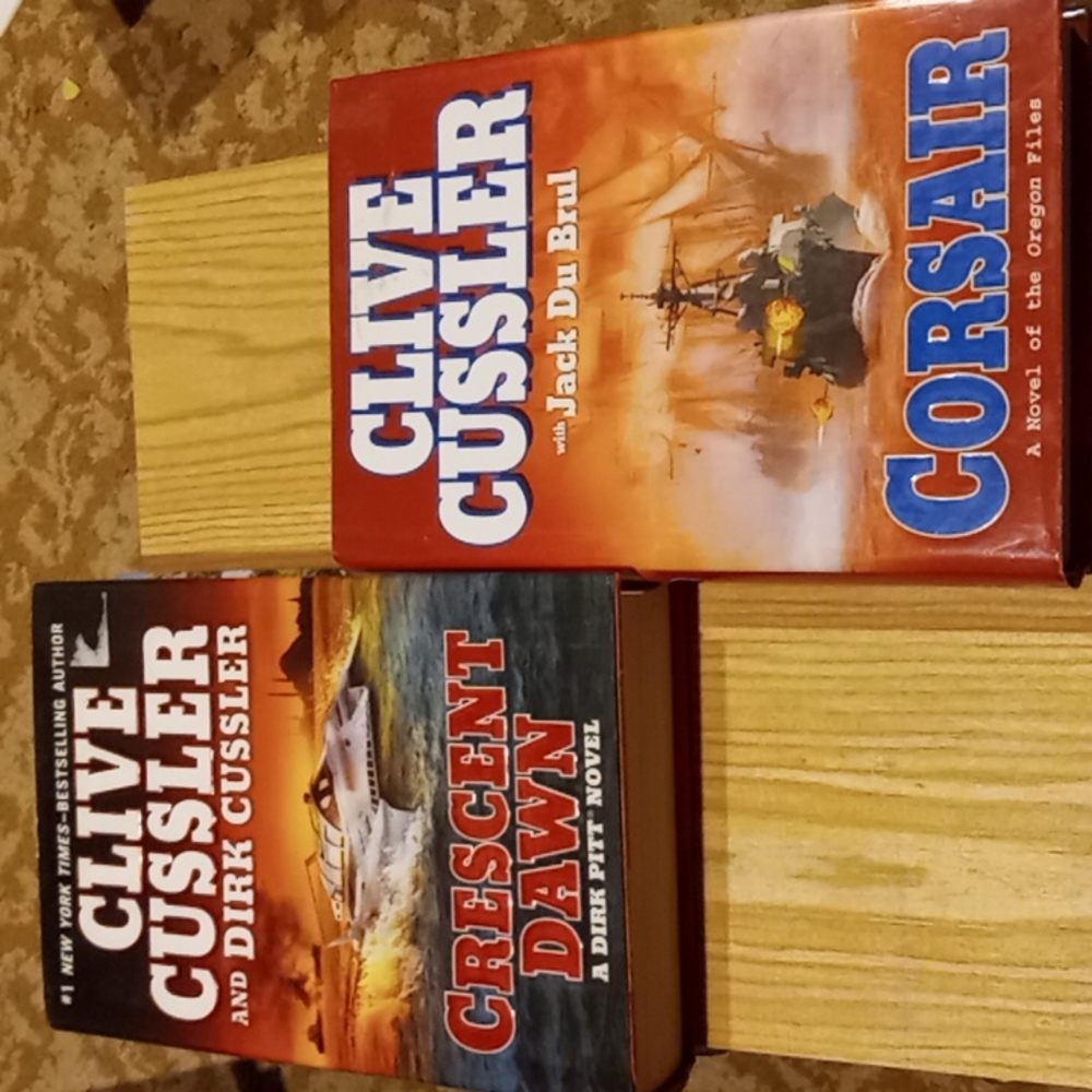 Hardback Clive Cussler novels, unread $7 each or $13 together.